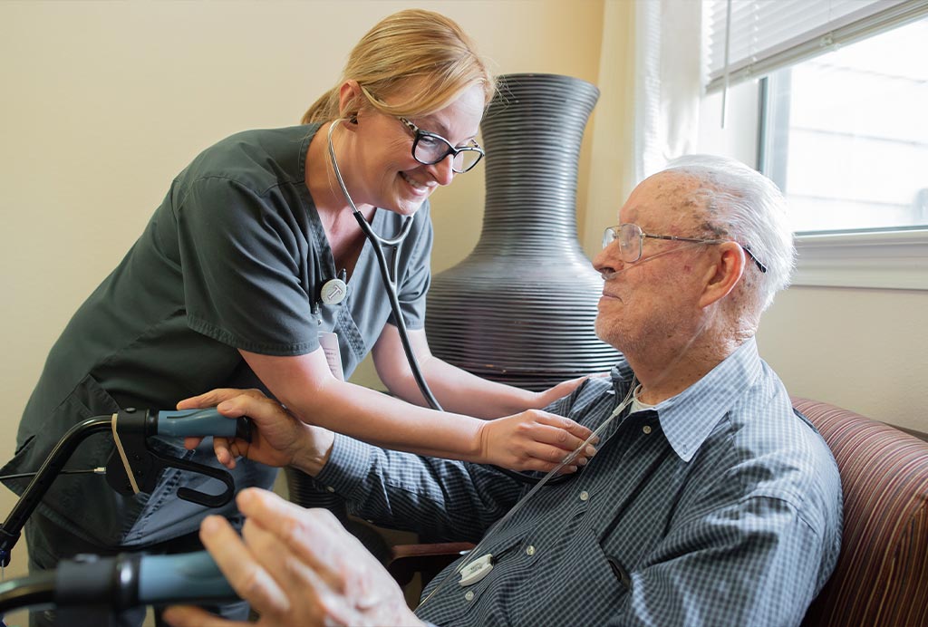 Caregiver using a stethoscope to check an older resident's health at a Franklin Park Senior Living community.