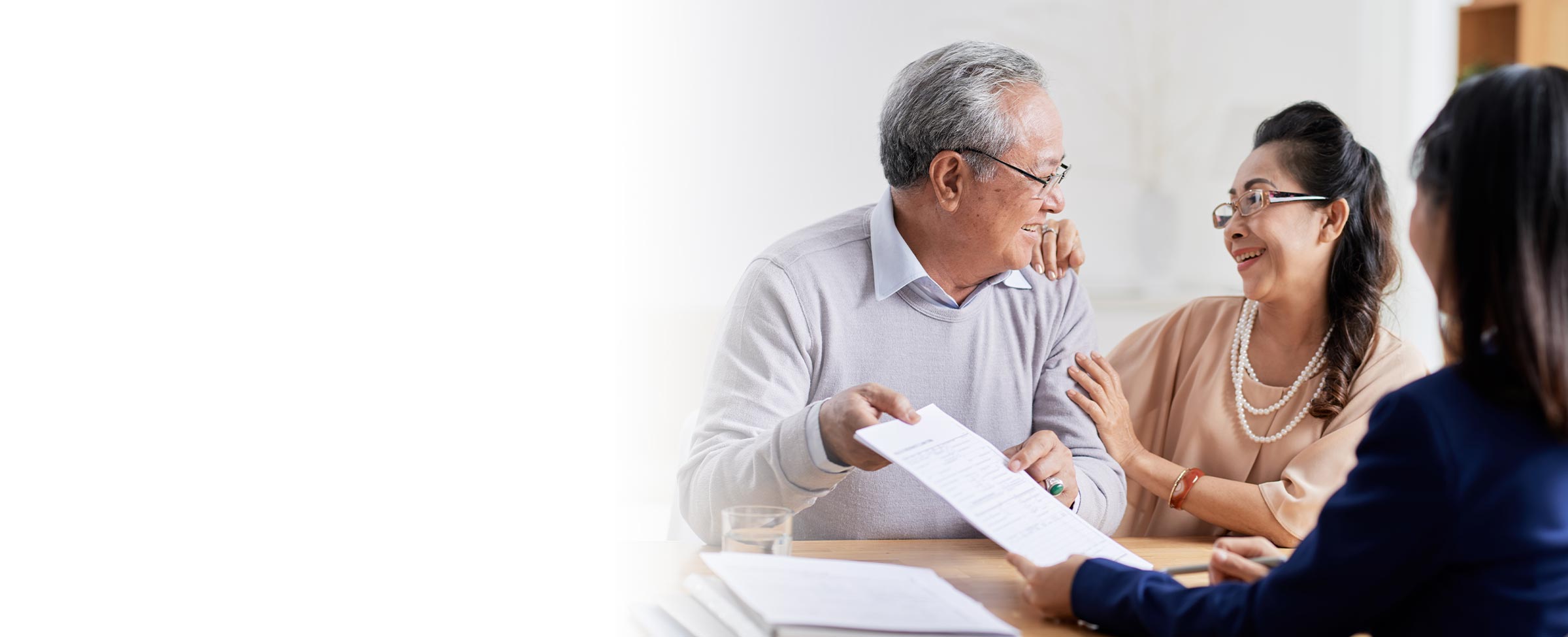 Older couple smiling while reviewing paperwork with a professional at Franklin Park Senior Living.