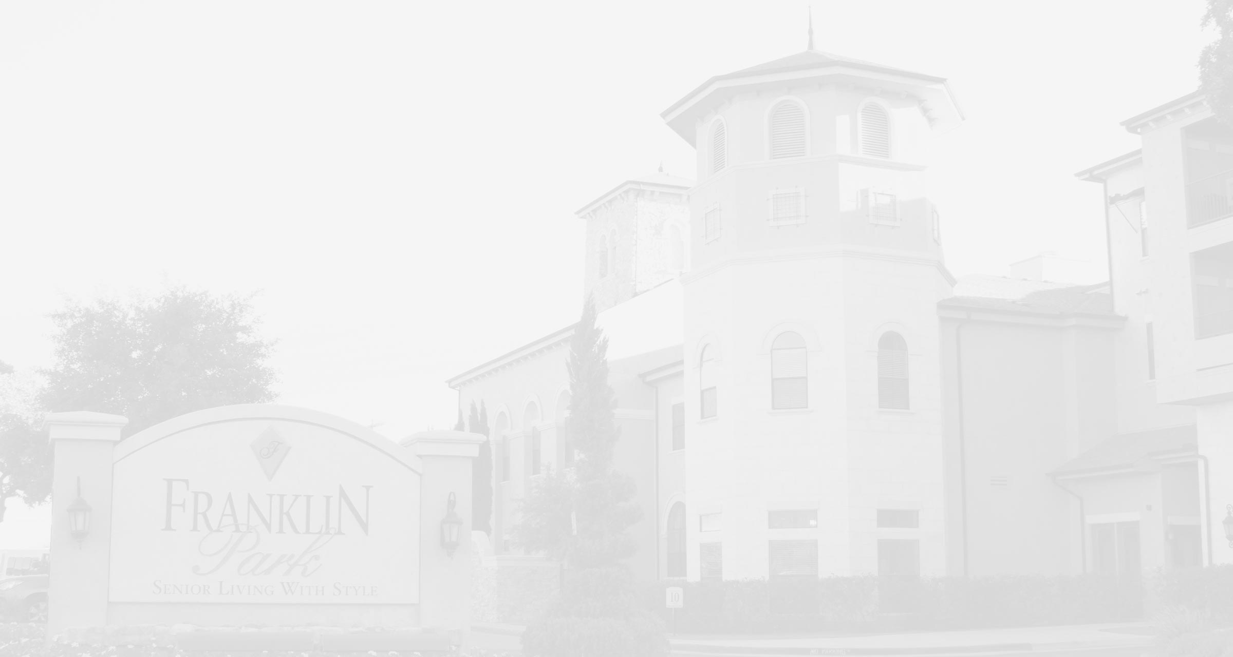 Exterior of a Franklin Park Senior Living community featuring Mediterranean-inspired architecture, a decorative tower, and the Franklin Park entrance sign.