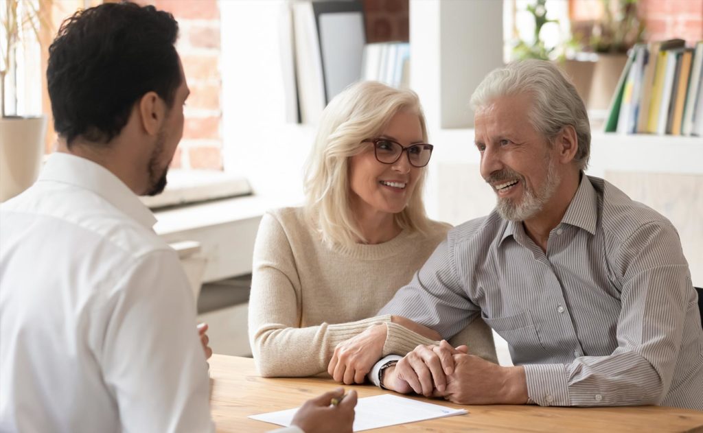Older couple smiling while meeting with a professional to discuss services offered by Franklin Park Senior Living.